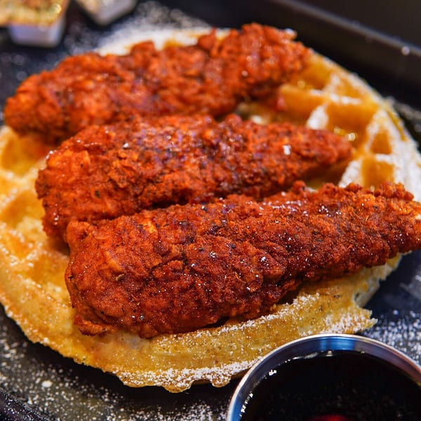 Haazs' halal chicken and waffles, with crispy red chicken tenders on a waffle, dusted with powdered sugar.