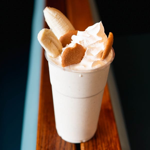 A Haazs banana pudding milkshake with whipped cream, banana slices, and vanilla wafers.