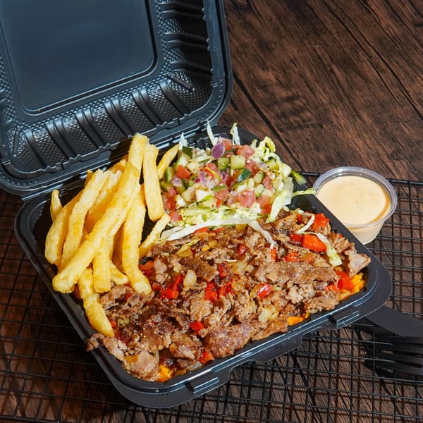 Halal Haazs platter with seasoned meat, fries, salad, and sauce in a black takeout container.